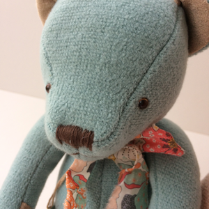 Beautiful Blue Teddy Bear - A timeless gift This beautiful blue teddy bear arrives in a floral cloth bag with a matching floral bow tie around his neck. Close up of blue teddy bear face