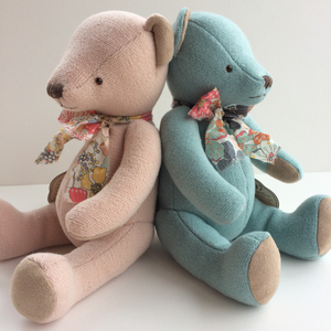 Beautiful Blue Teddy Bear - A timeless gift This beautiful blue teddy bear arrives in a floral cloth bag with a matching floral bow tie around his neck. This classic high quality teddy bear is timeless and will be treasured for years to come. Showng pink and blue teddy bears together sitting back to back.