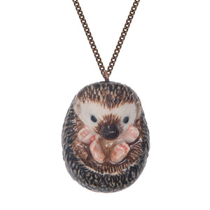 Hand-painted porcelain baby hedgehog necklace This curled up hedgehog necklace is a beautiful gift for someone who loves nature.  The superb intricate design features four pink feet, a black nose, and black eyes.  This necklace is from a range of hand-painted porcelain necklaces that have amazing detailed features. 