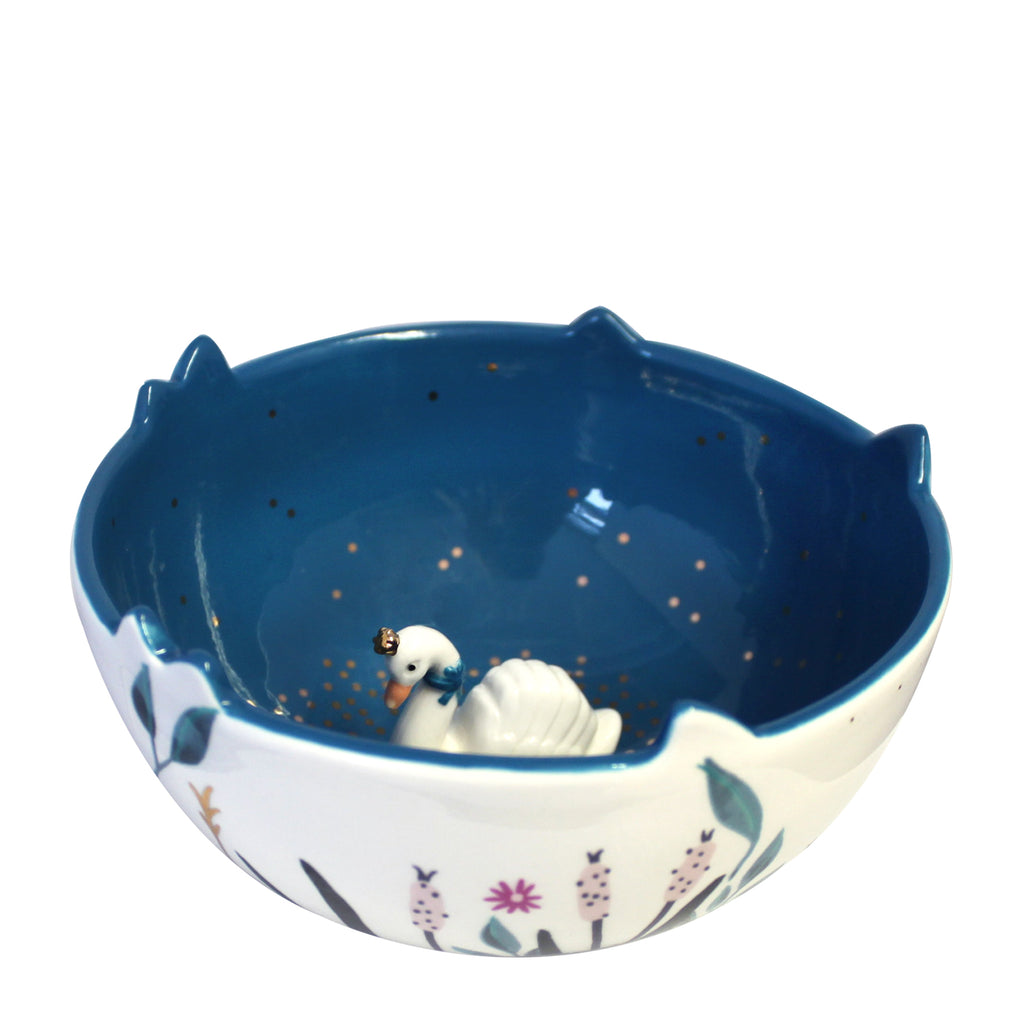 Aerial view of Swan Bowl. A lovely Swan Bowl - perfect for trinkets, jewellery or treats This elegant swan bowl depicts a pretty riverbank with floral designs decorating the outside of this bowl. Inside, there's a deep blue colour representing the water with gold dots glistening on the surface. A regal white swan wearing a gold crown, shelters at the bottom of the bowl.